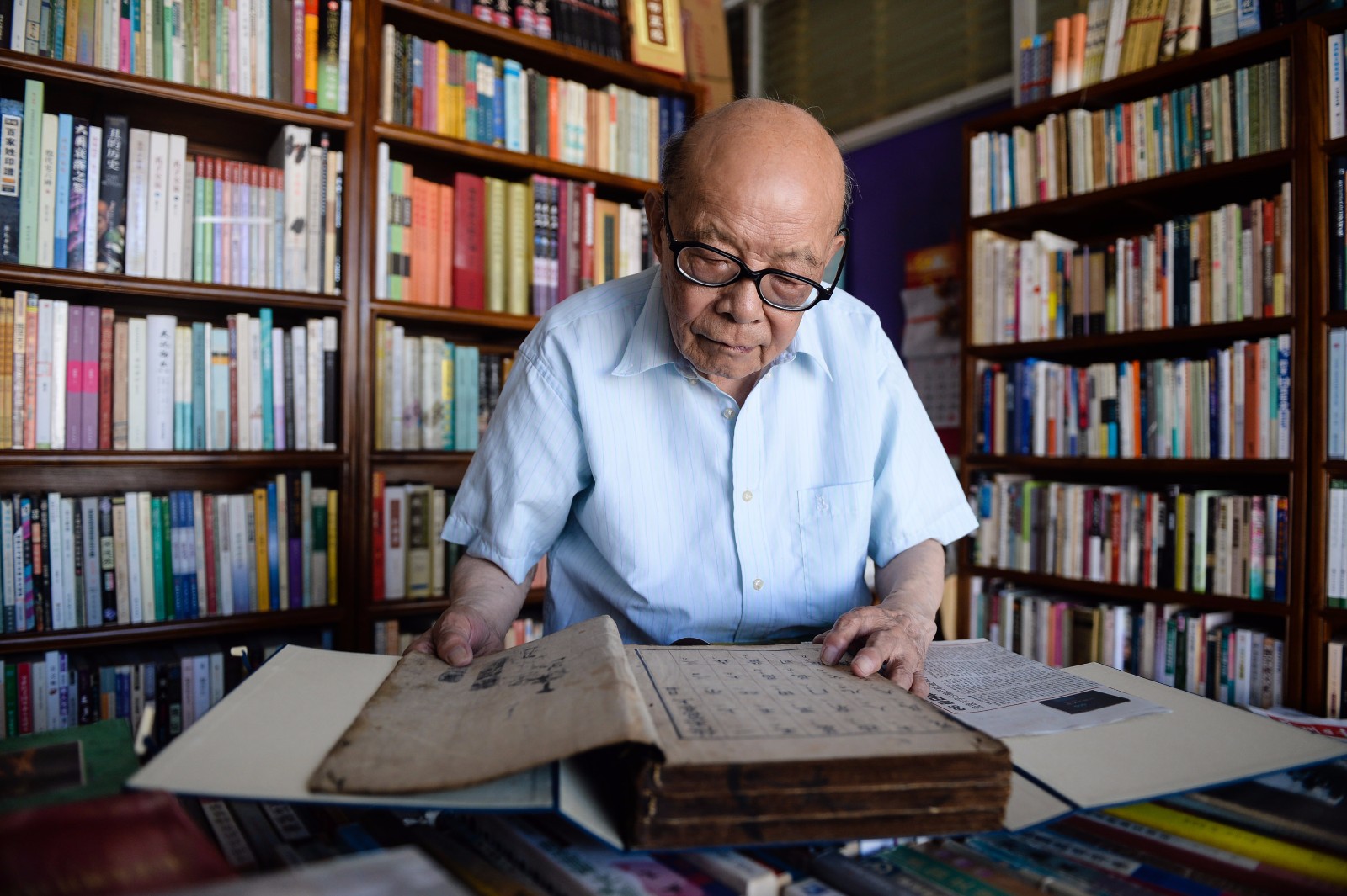   7月18日，江澄波老人在“文学山房”旧书店查看一本收藏的古书。 